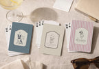 Playing cards with dog illustrations and text on a textured surface with a glass of wine and sunglasses. Wedding Party Favors