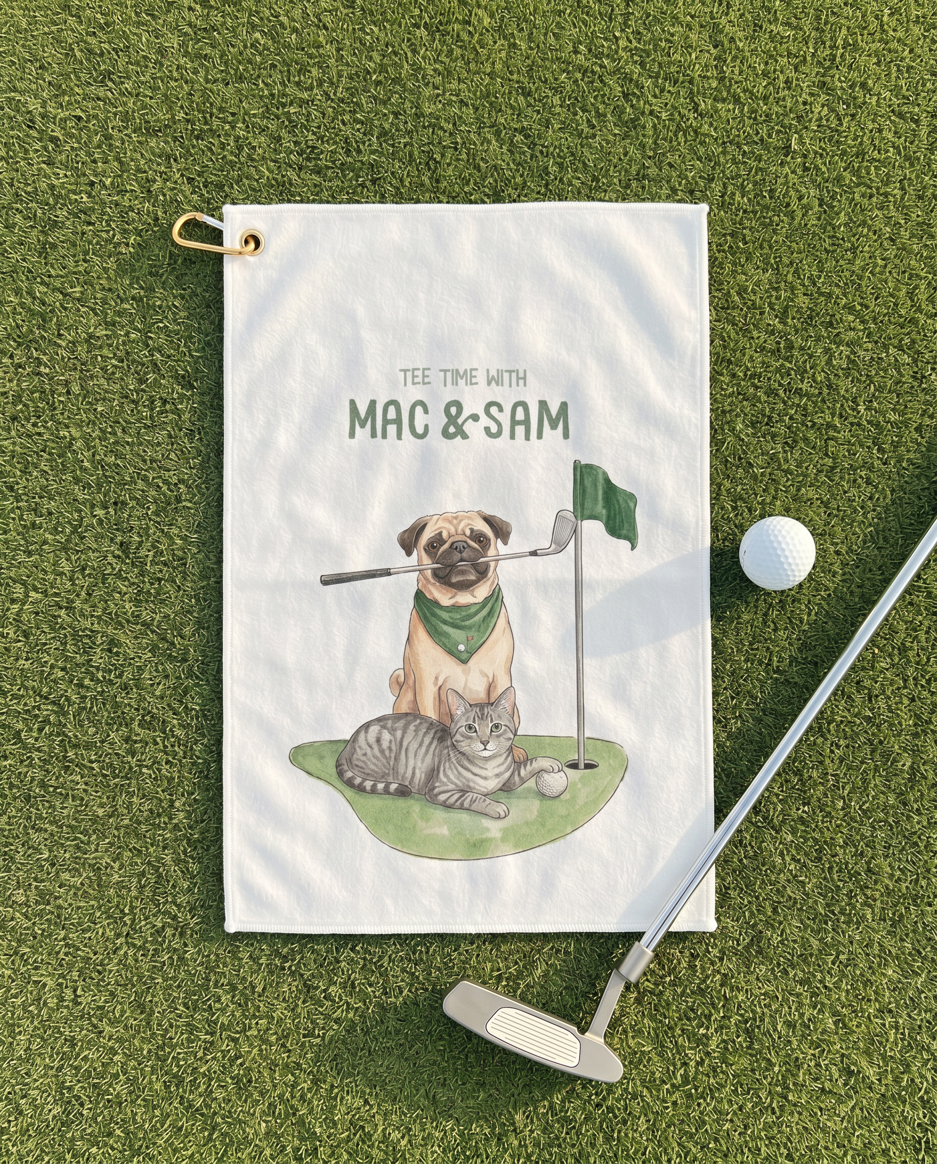 Golf towel with illustration of a pug and cat playing golf, placed on grass with a golf club and ball.