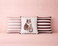 Three pillows with striped and cat print designs on a pink background