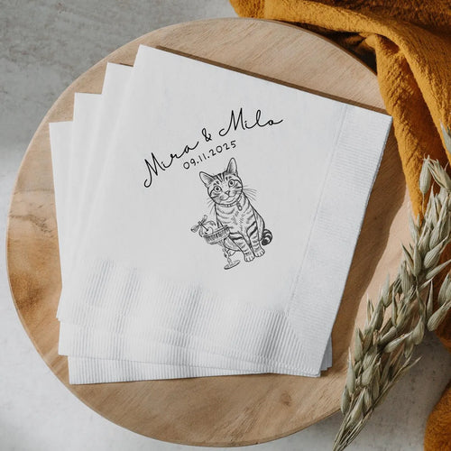 White napkins with a cat illustration and text on a wooden surface