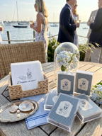 Outdoor setting with custom wedding playing cards, napkins, and a decorative tray on a table by the water.