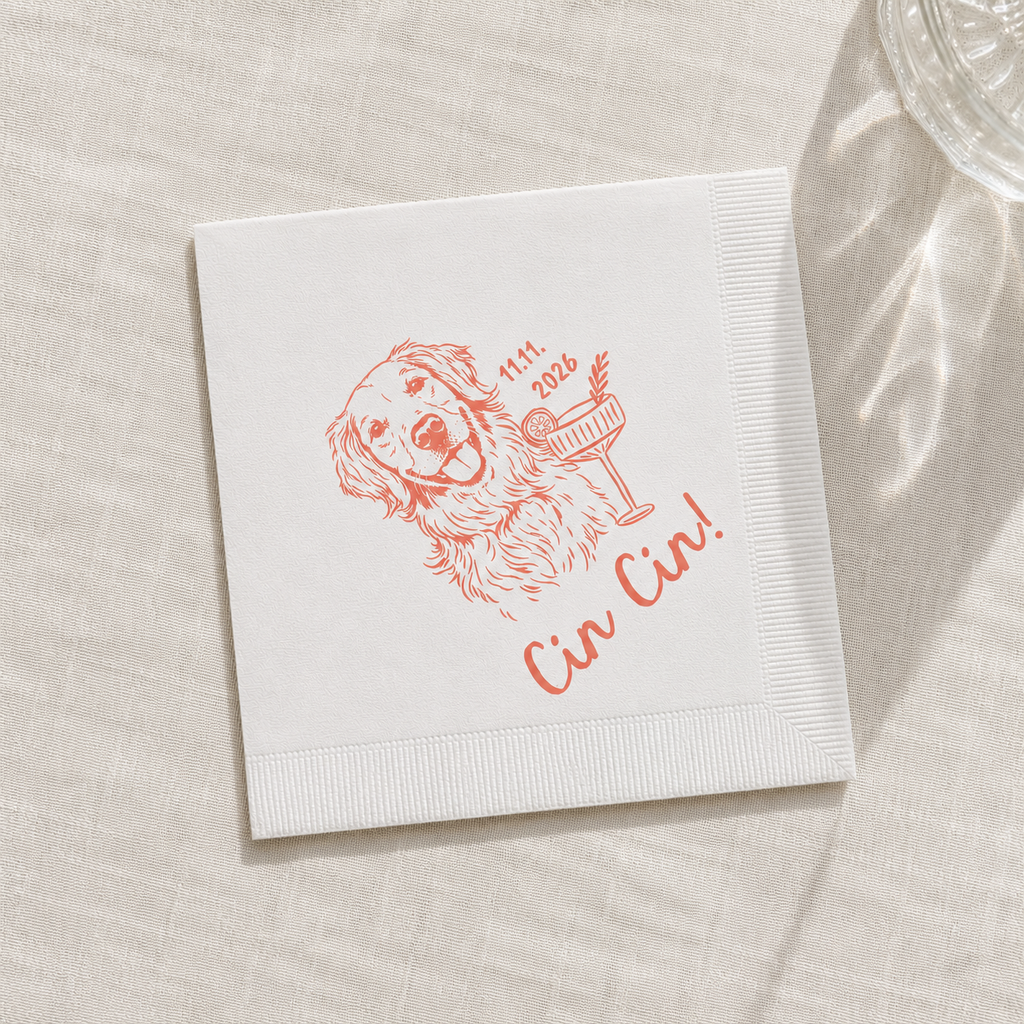 A square white paper napkin with a red line-art illustration of a dog holding a cocktail glass and the text 'Cin Cin!' and '11th 2026', placed on a light beige textured surface with soft shadows.