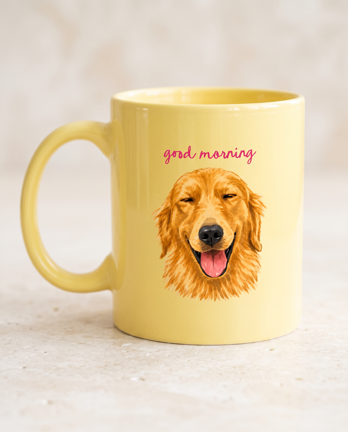 A yellow ceramic mug with a handle, featuring a printed illustration of a golden retriever dog and the words 'good morning' in pink script on the front, set against a light beige textured background.