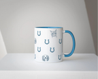Custom mug with cat and dog illustrations and horseshoes and blue handle on a white surface