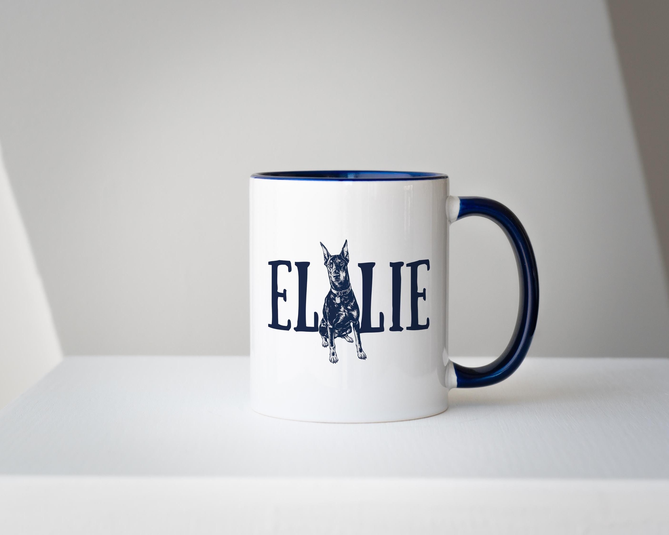 White mug with blue interior and handle, featuring a dog illustration and the name on a white background.