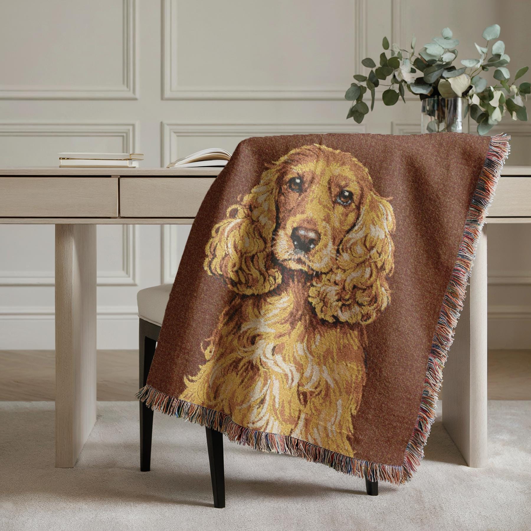 Brown blanket with a dog design draped over a chair in a room with a desk and plants.