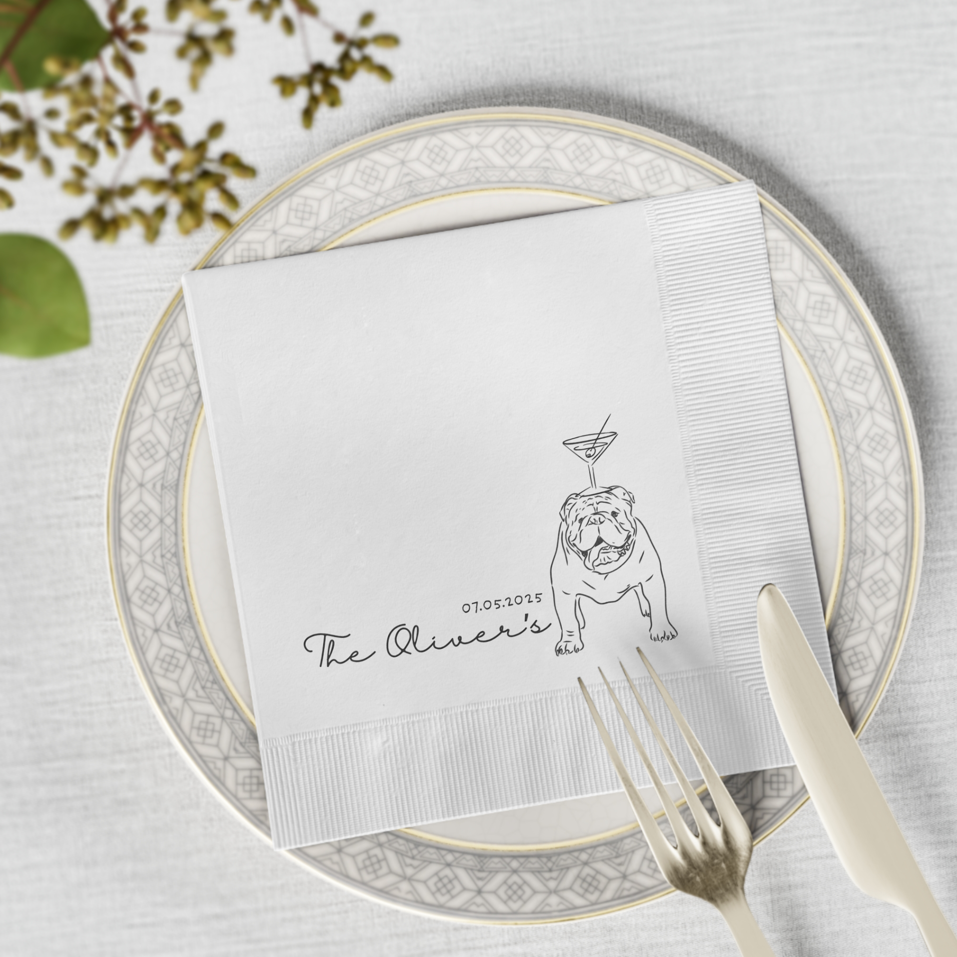 Cocktail napkin with bulldog illustration and 'The Oliver's' text on a place setting with plates and cutlery.