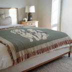 Bed with a green blanket featuring a Dachshund in a bedroom setting.