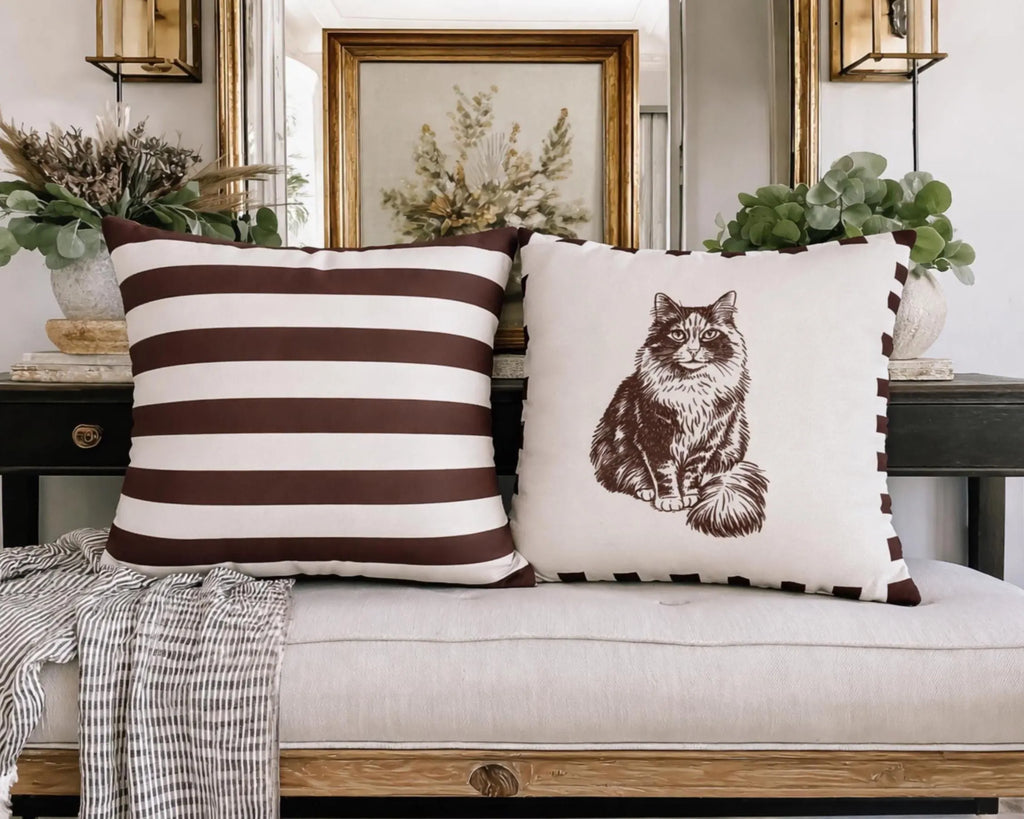 Two decorative pillows on a sofa with a striped pattern and a cat illustration.