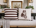 Two decorative pillows on a sofa with a striped pattern and a cat illustration.