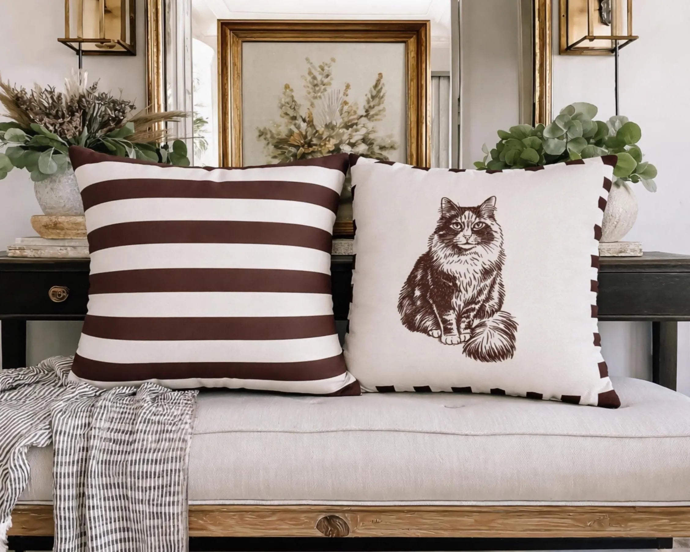 Two decorative pillows on a sofa with a striped pattern and a cat illustration.