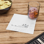 Napkin with a logo on a wooden table with a glass of iced tea and chips.