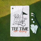 Golf towel with dog illustration and 'Tee Time with Ralphy' text on a green surface with golf accessories.