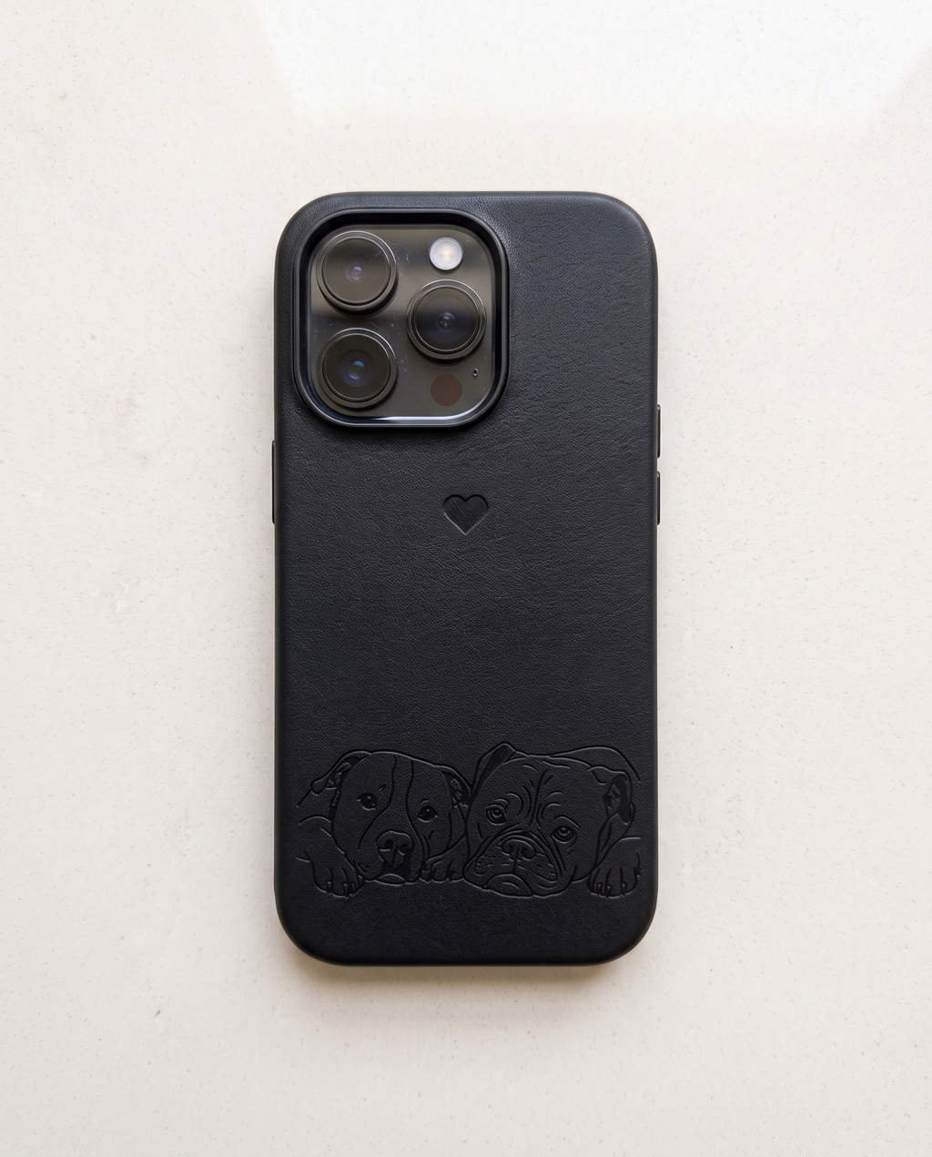 A black textured leather phone case with an embossed puppy design along the bottom and a small heart logo, shown on a light off-white background.
