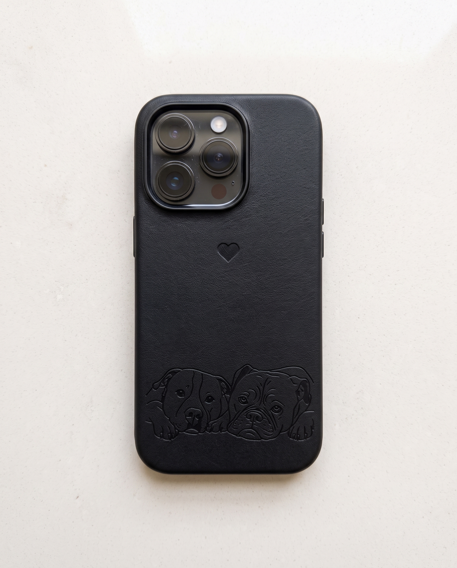 A black textured leather phone case with an embossed puppy design along the bottom and a small heart logo, shown on a light off-white background.