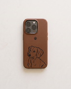 A brown leather phone case featuring a black line art illustration of a dachshund and a small black paw print, shown on a light beige textured background.