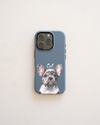 A slate blue phone case featuring a printed illustration of a French Bulldog named 'Cal' in white script, displayed on a light beige textured surface.