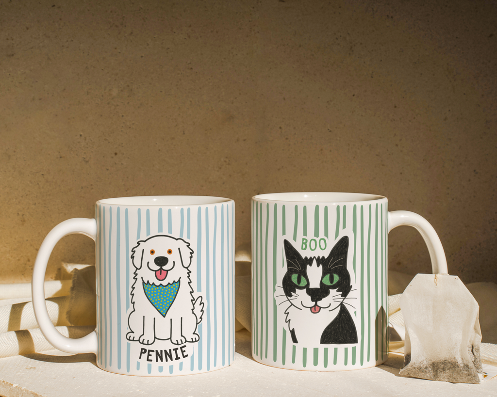 Two mugs with dog and cat illustrations on a textured surface