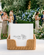 Wedding reception with guests and a table with a basket and napkins in an outdoor setting.