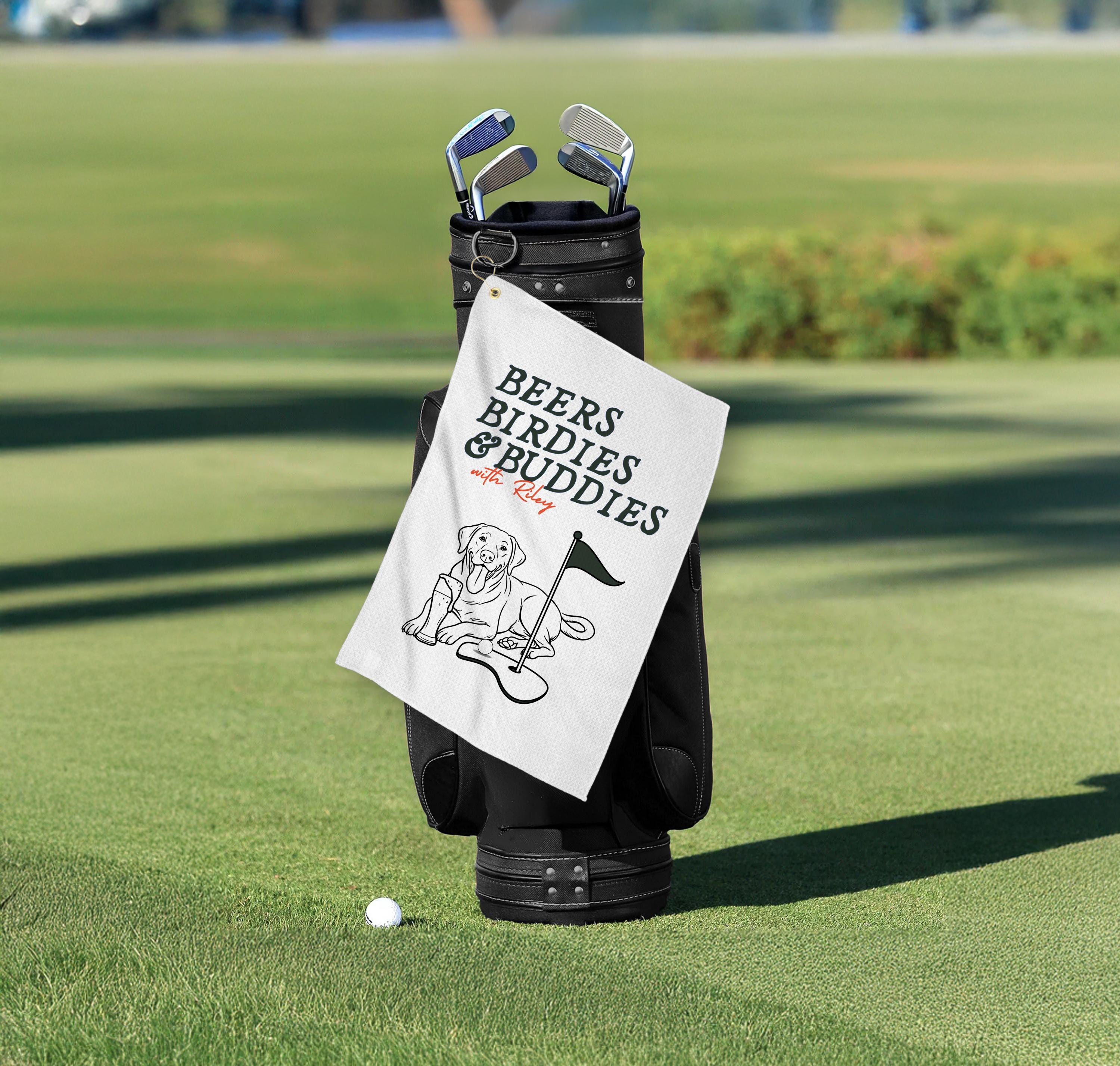 Golf bag with a towel labeled 'Beers, Birdies & Buddies' on a golf course.