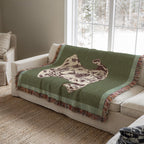 Green blanket with a decorative pattern and dog draped over a white sofa in a living room.