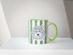 Green and white striped mug with a dog illustration on a white surface