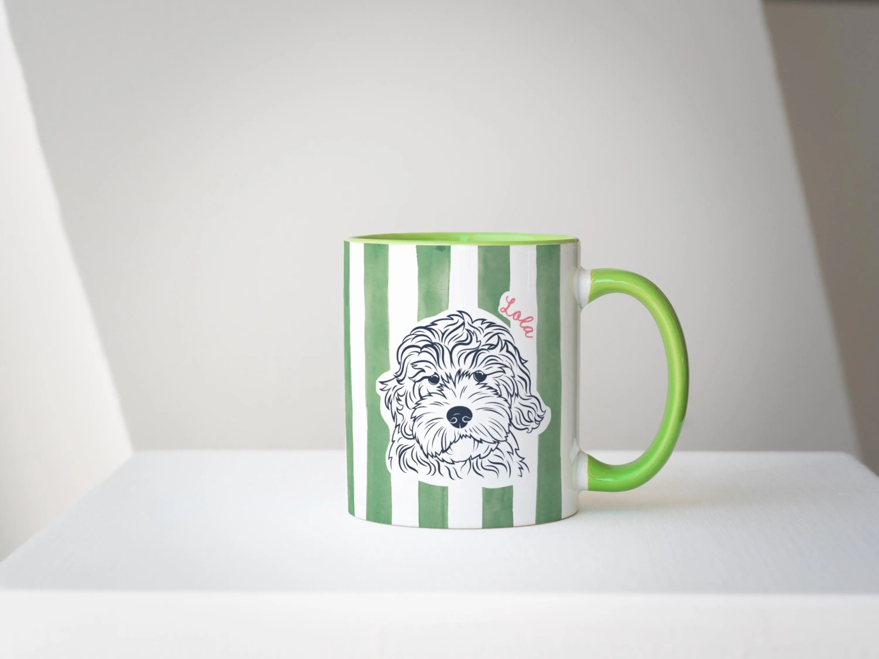 Green and white striped mug with a dog illustration on a white surface