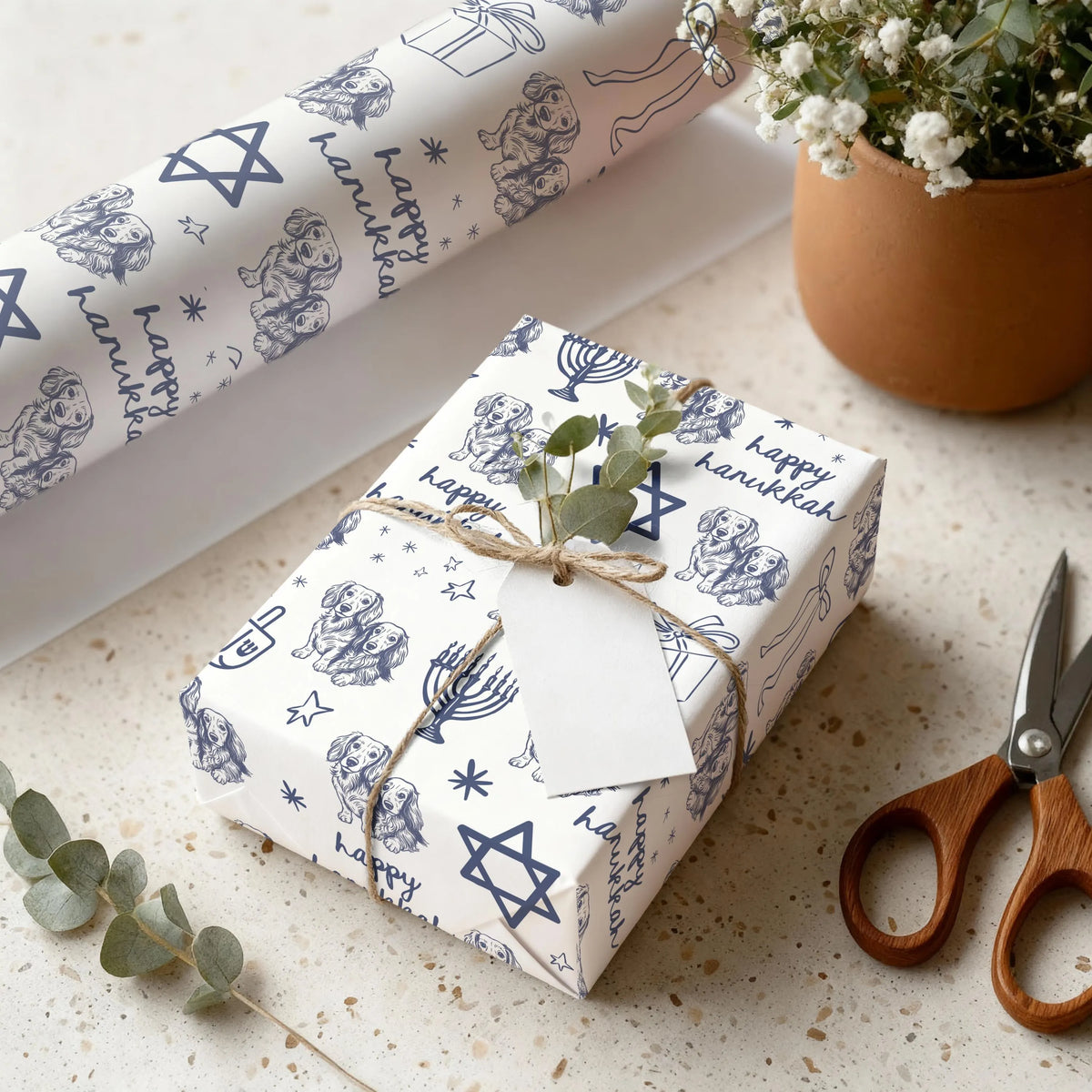 Gift wrapped in custom dog 'Happy Hanukkah' paper with a plant and scissors on a surface