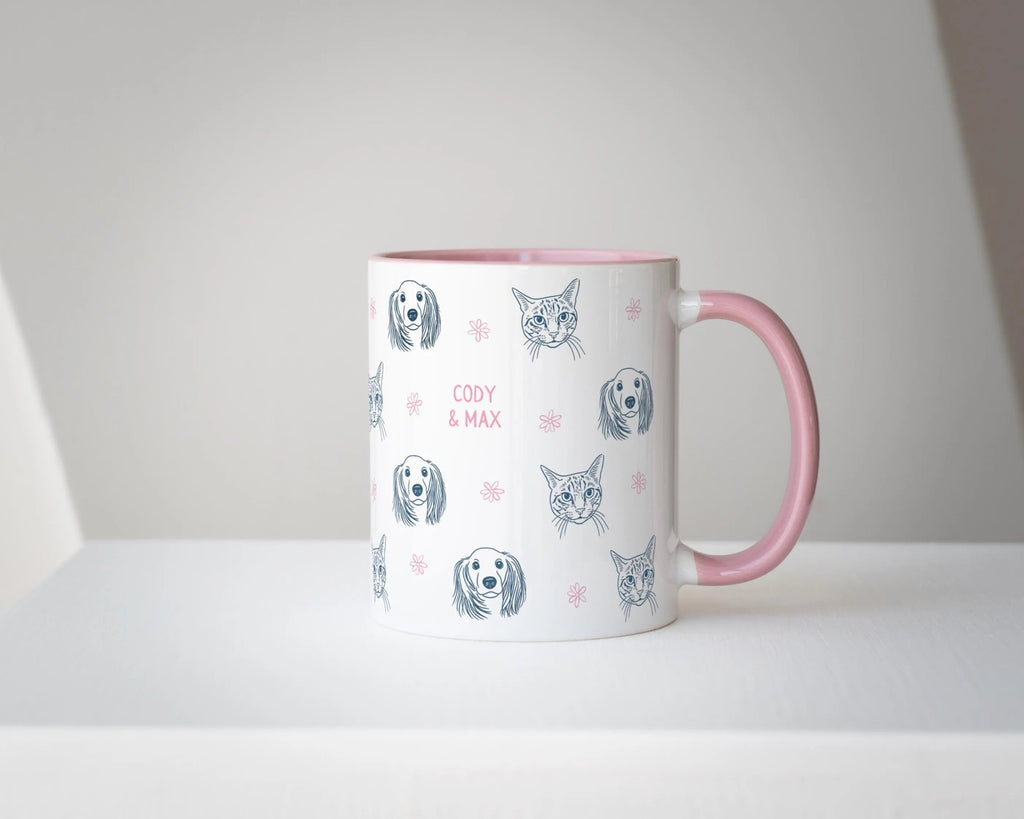 Custom mug with cat and dog illustrations and pink handle on a white surface