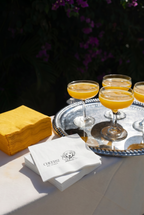 Glasses of orange juice on a silver tray with yellow napkins and white napkins on a table.