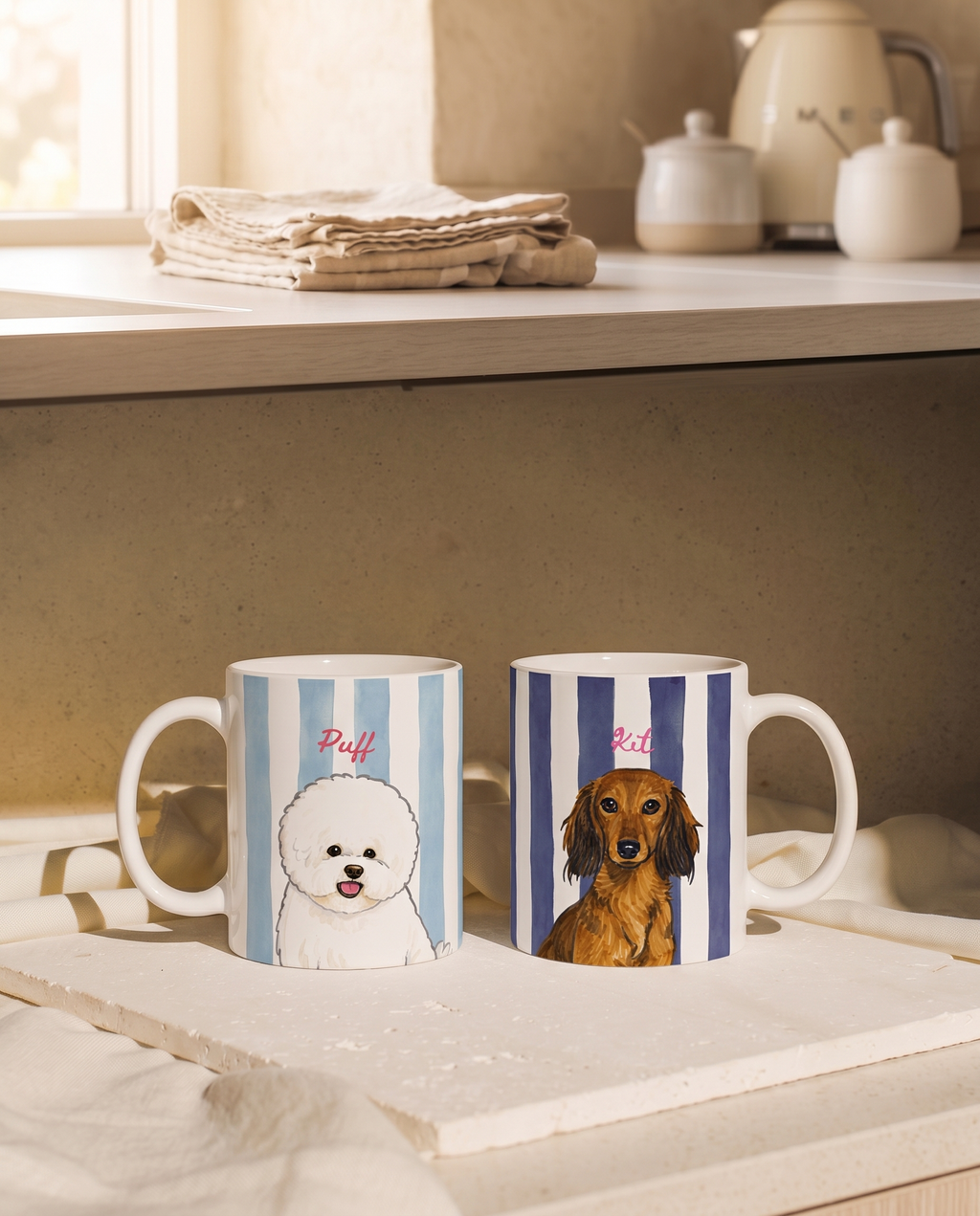 Two ceramic mugs with blue and white vertical stripes, shown on a tabletop in a warm kitchen setting. One mug features a white dog illustration with the name 'Puff' in red, and the other features a brown dachshund with the same red text.