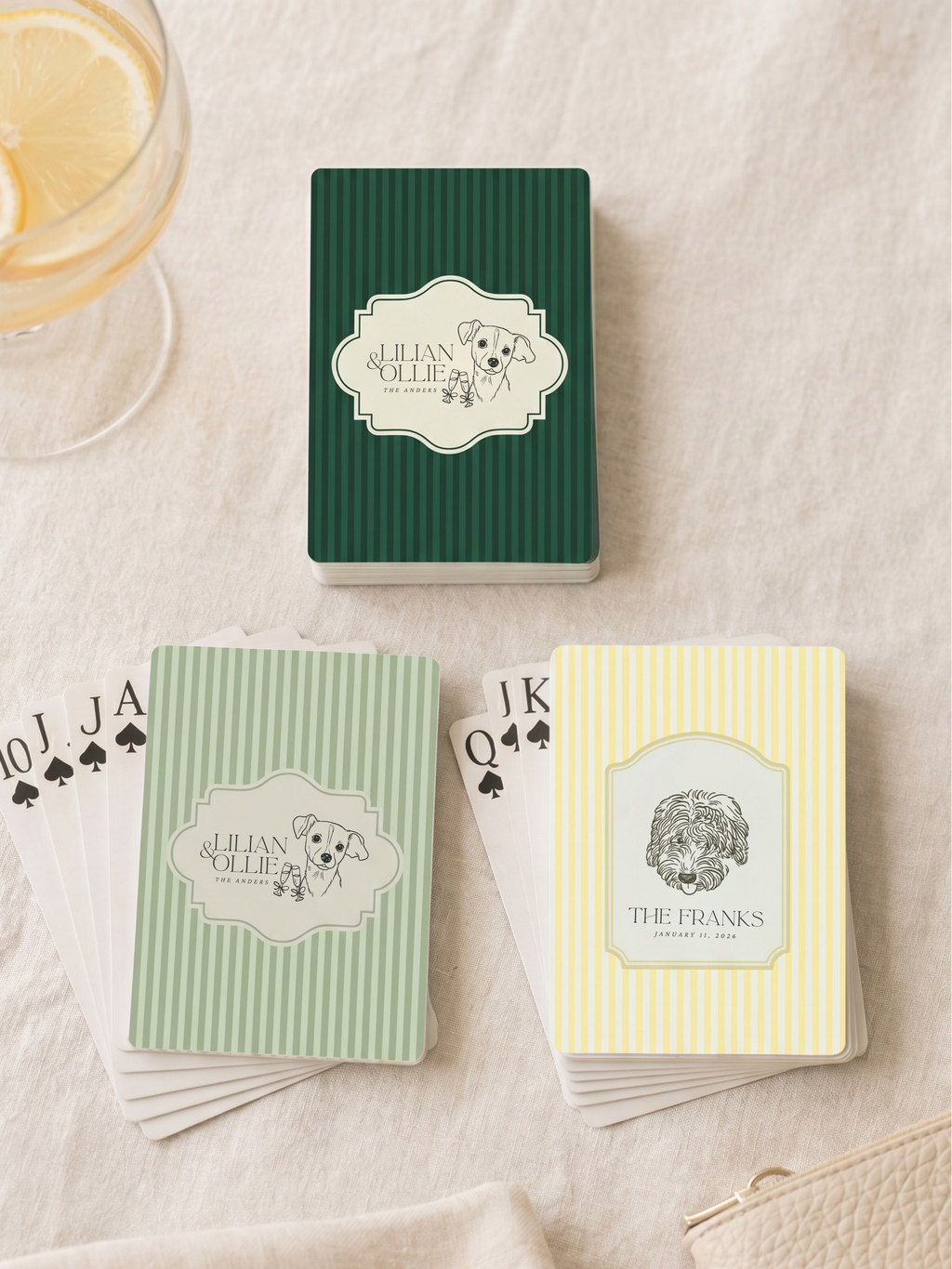 Three decks of playing cards with custom designs on a light fabric background