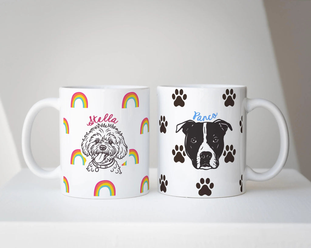 Two mugs with dog illustrations - custom dog mug with rainbows, and custom dog mug with paw icons and names on a white surface.