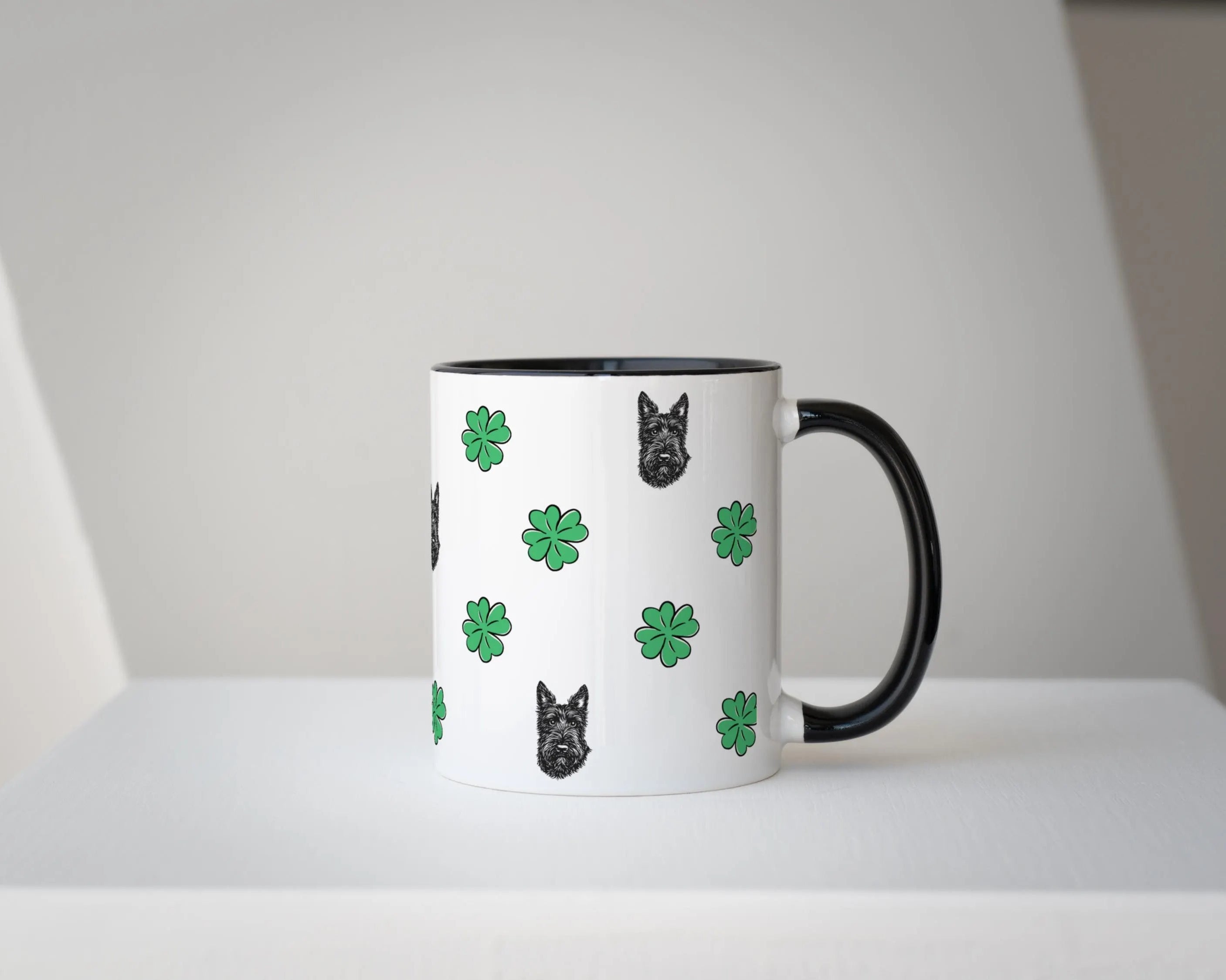 White mug with black handle featuring dog and clover pattern on a white background