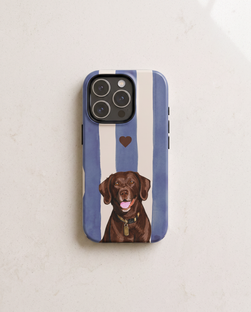 A phone case featuring a blue and white vertical stripe pattern with a brown heart and a painted chocolate Labrador retriever at the bottom, shown on a light marble surface.