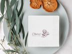 White napkin with a printed design on a gray plate with dried oranges and eucalyptus leaves.