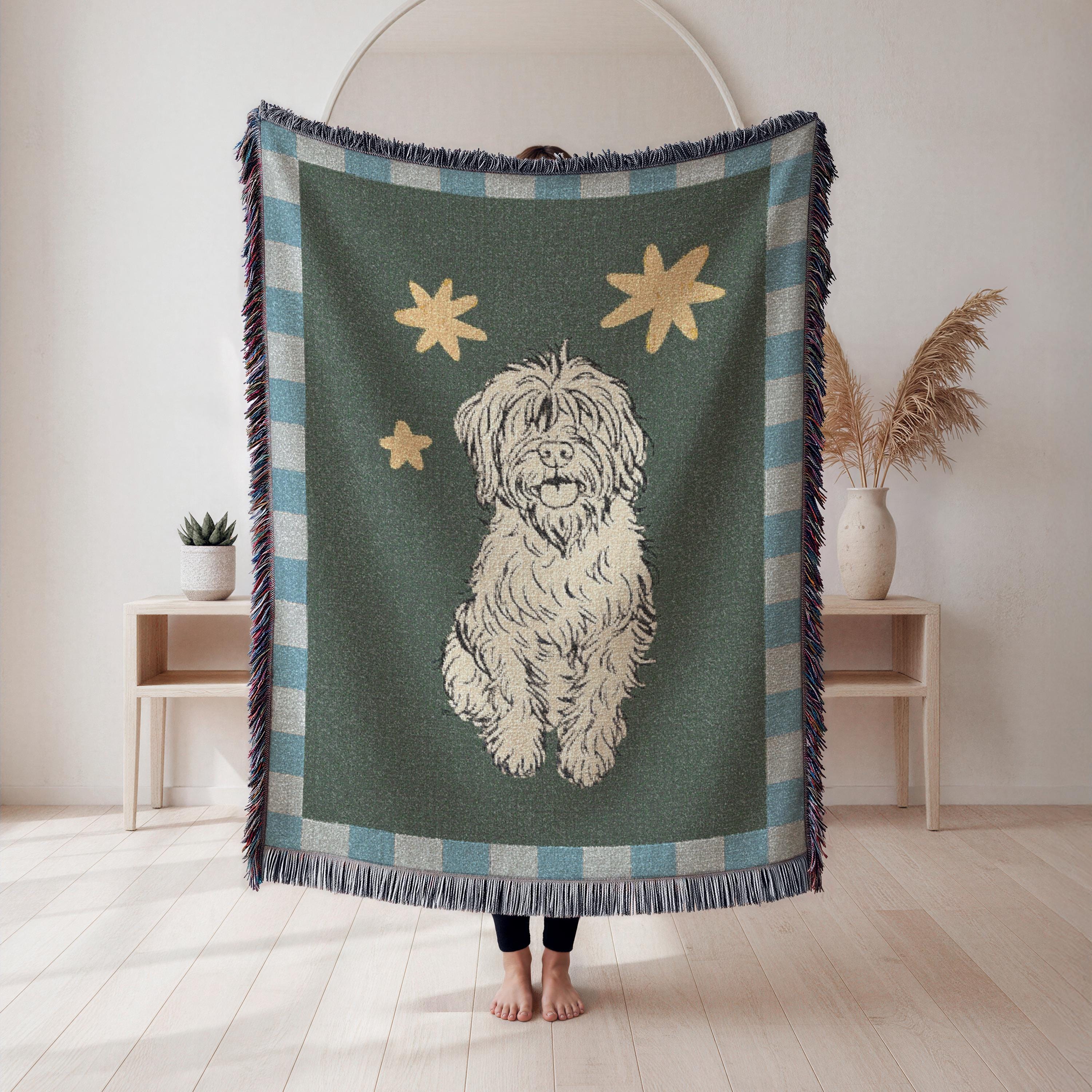 Person holding a blanket with a dog illustration and star pattern in a room.