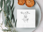 Note with a dog illustration and text on a white plate with dried fruits and eucalyptus leaves.