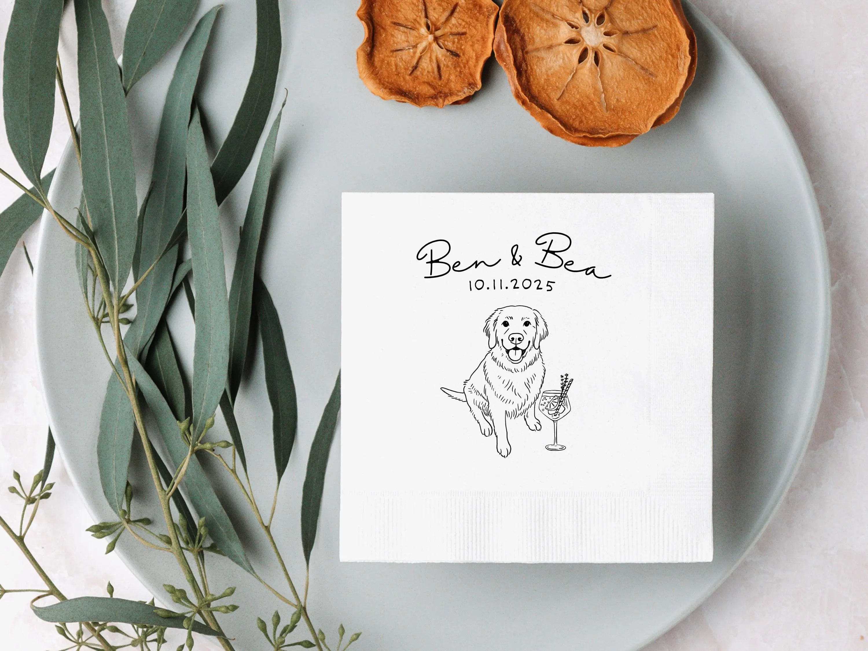 Note with a dog illustration and text on a white plate with dried fruits and eucalyptus leaves.
