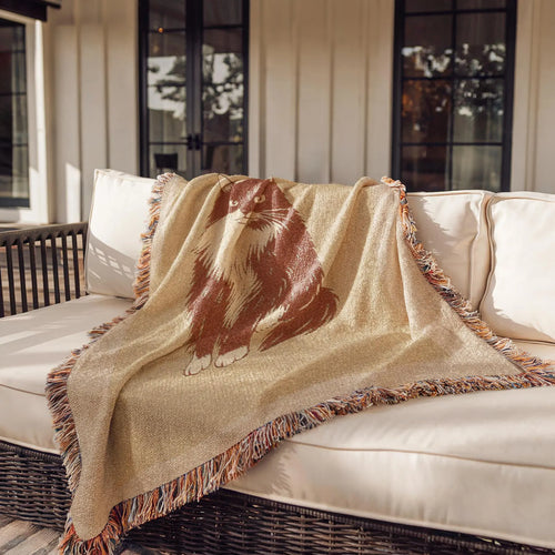 Beige blanket with a brown animal design draped over a white outdoor sofa.